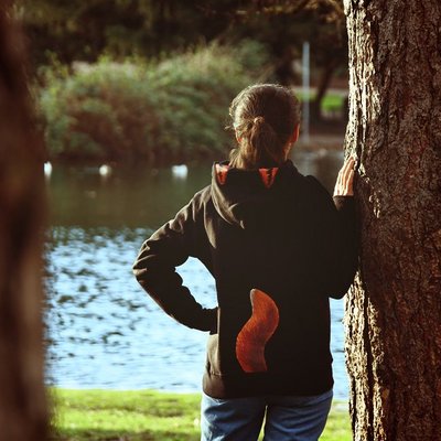 Auf dem Bild ist eine Frau von hinten vor einem See mit einem Pullover mit Fuchsschwanzaufdruck zu sehen
